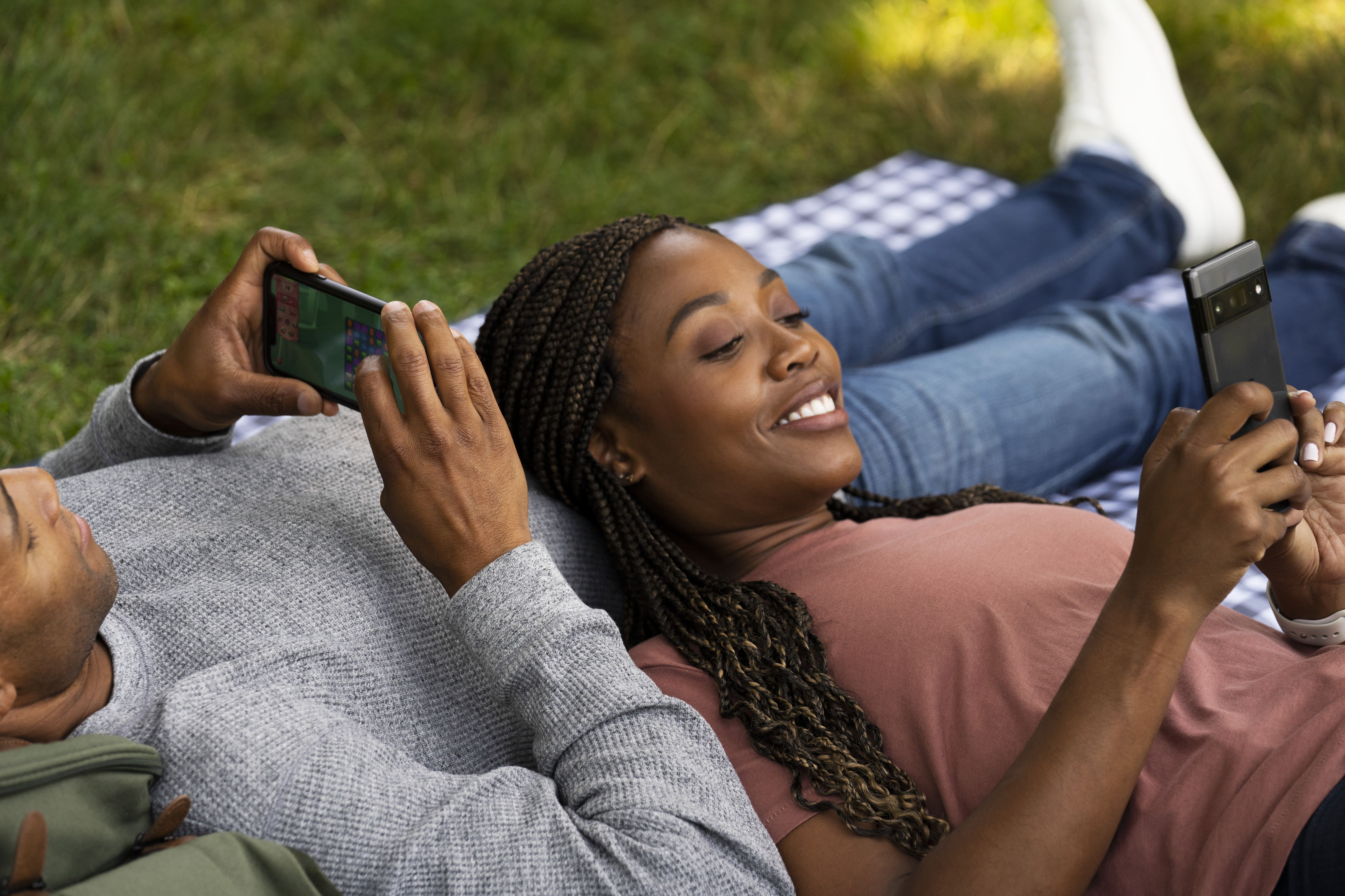 Una pareja feliz juega con los móviles en el exterior.