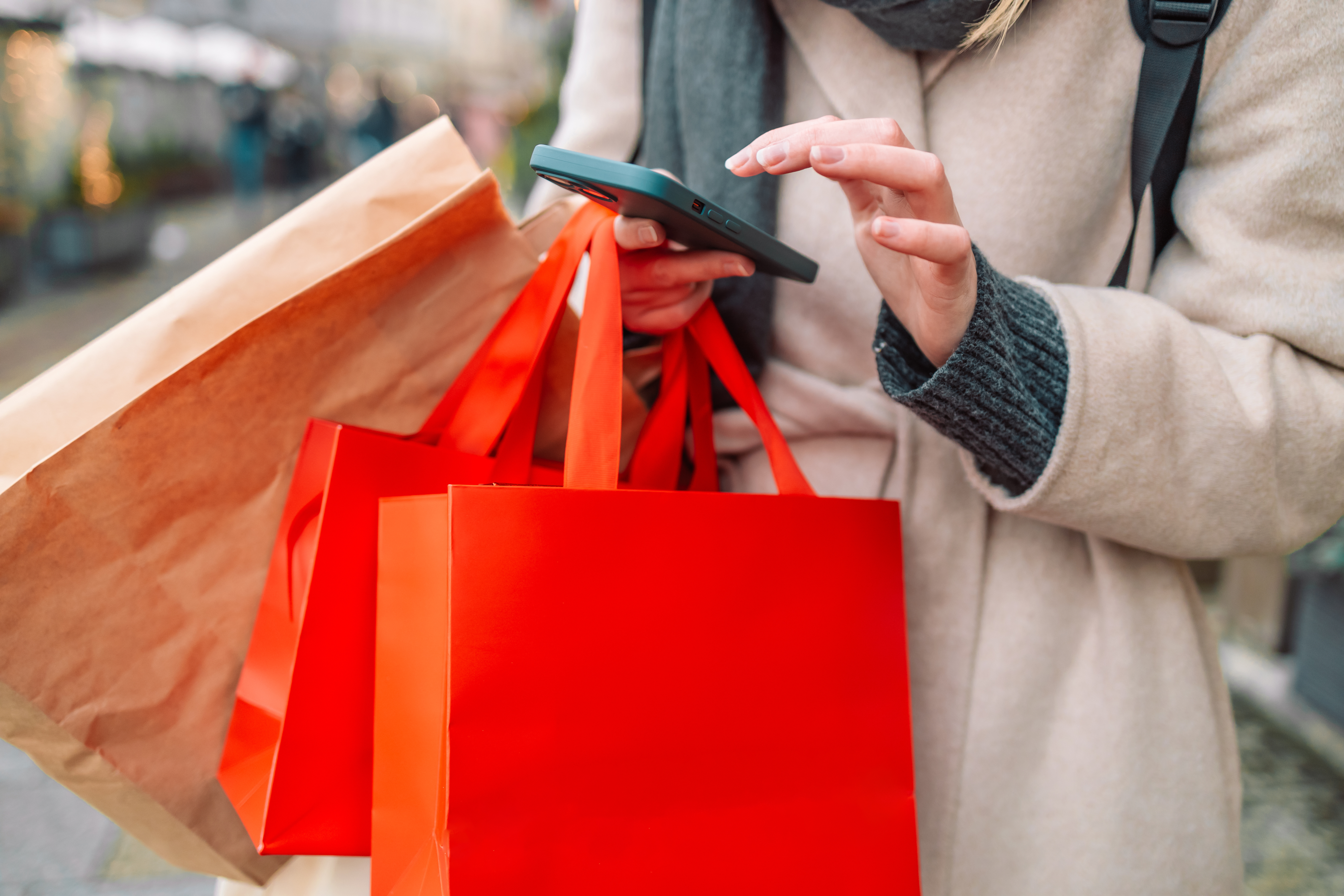 A woman looking at her phone while shopping for the holidays.