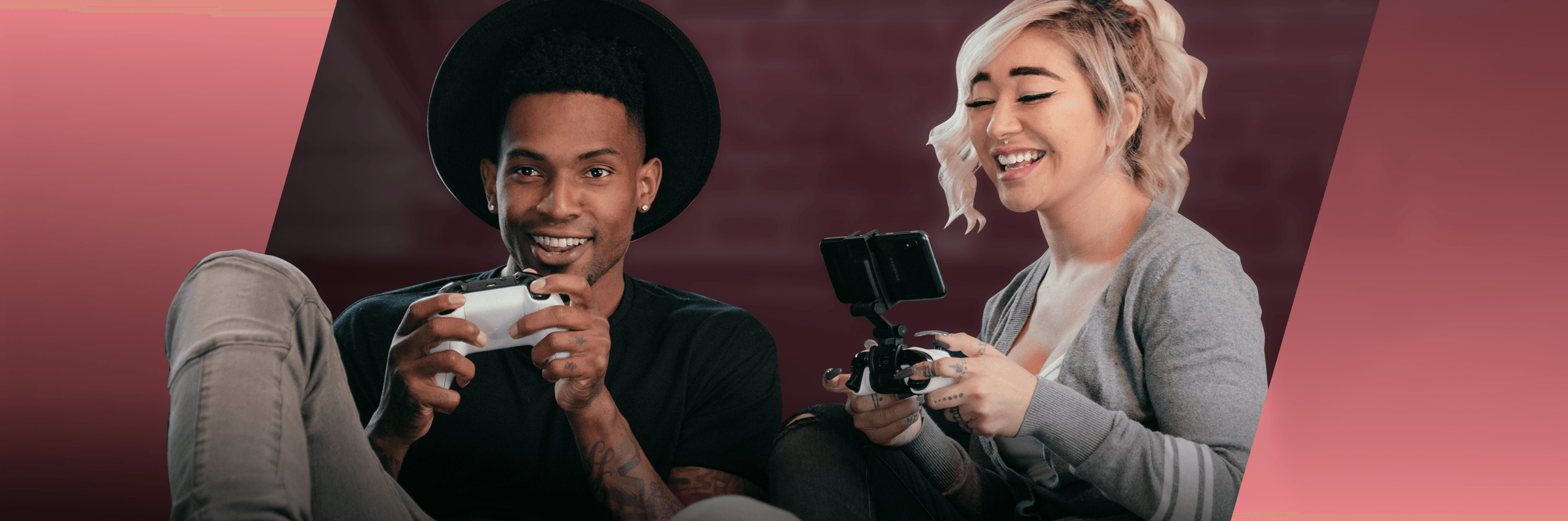 A happy young man plays XBOX while a young woman plays on a mobile phone next to him. 