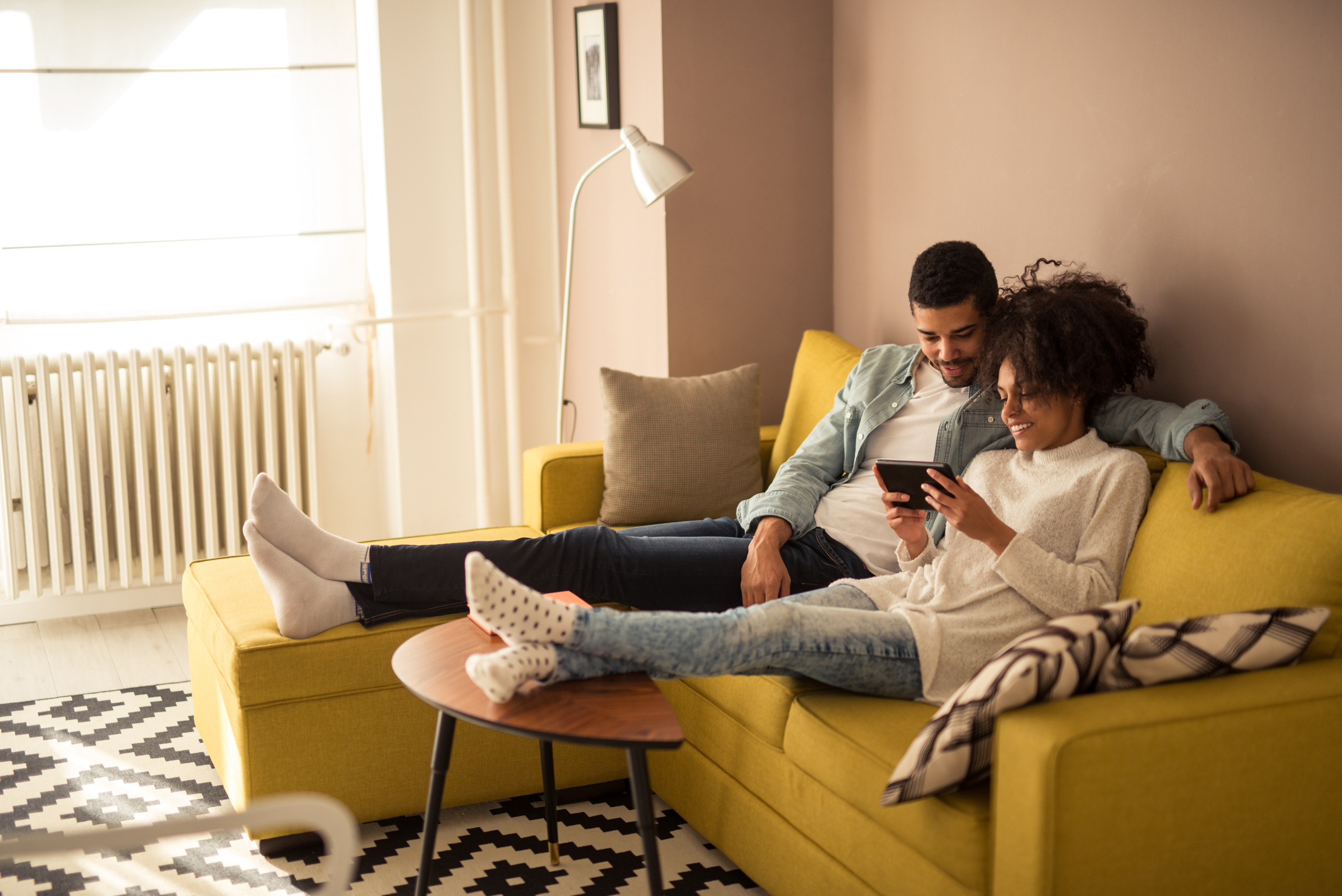 A couple sitting together and gaming on a phone.